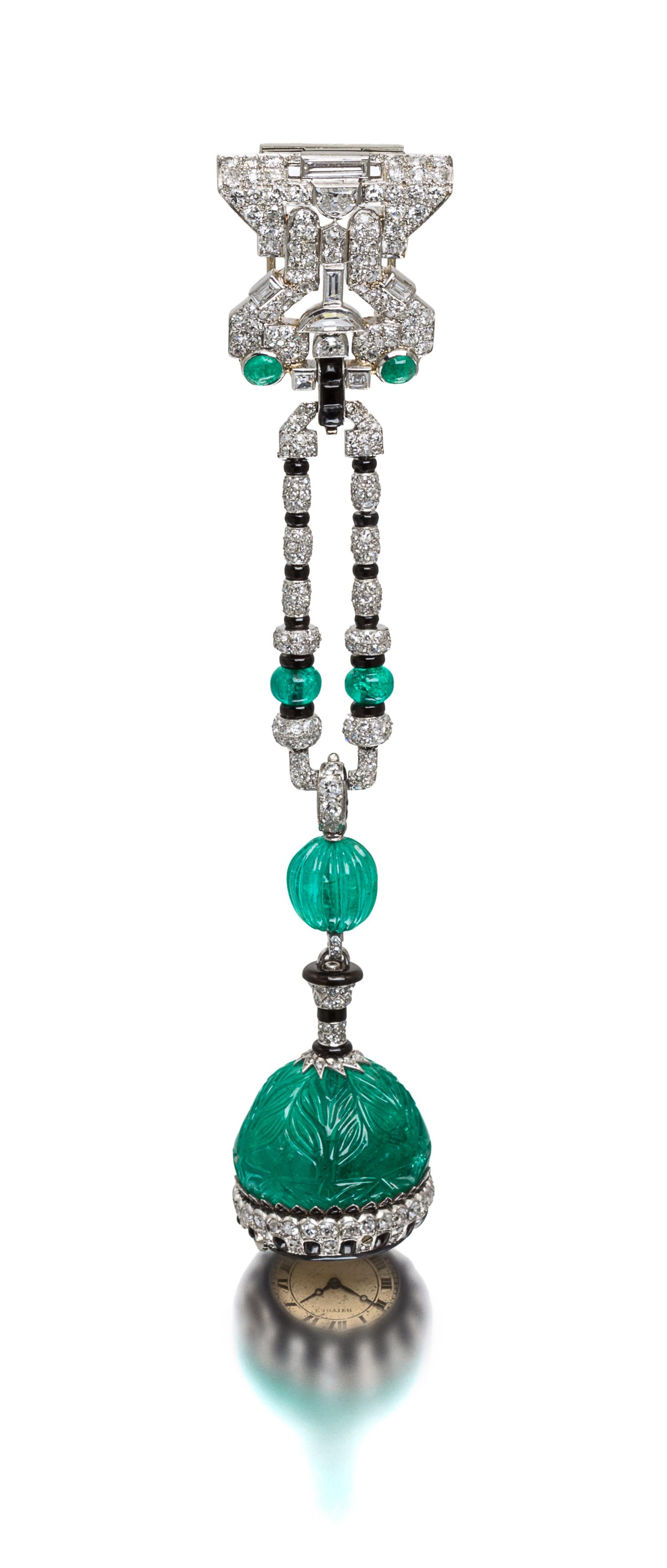 An Art Deco Platinum, Emerald, Diamond, Onyx and Enamel Lapel Watch, Cartier, 37.00 dwts.