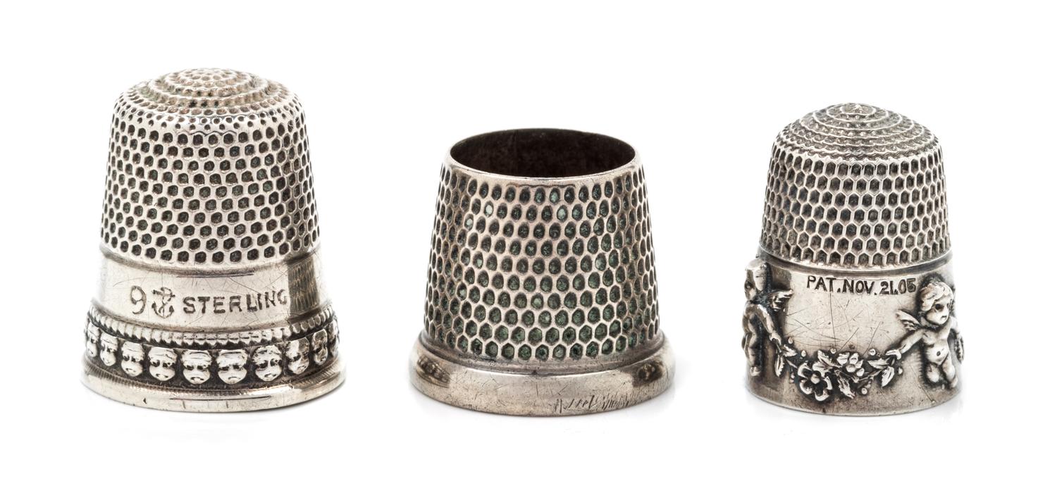 Three American Silver Thimbles, Various Makers, comprising an example with a rim worked to show putti masks, Goldsmith Stear & Co., New