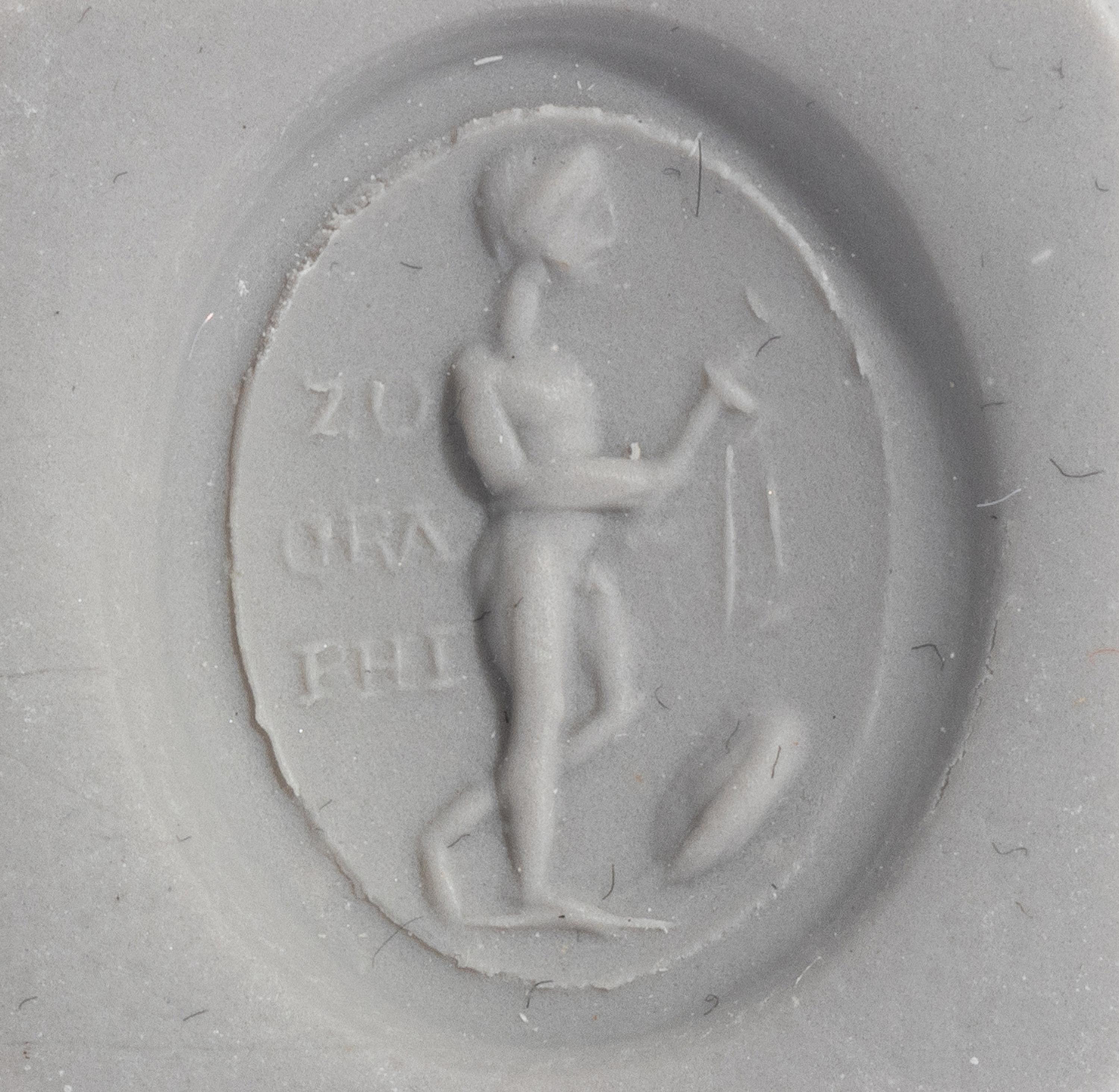 A Roman Gold and Plasma Finger Ring with a Figure Holding Tools and an Inscription
