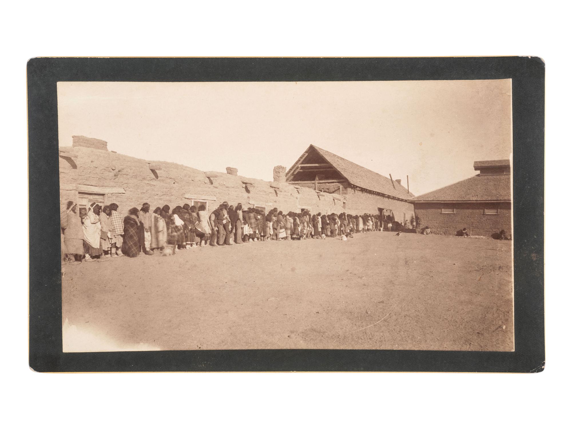 [NATIVE AMERICAN]. RANDALL, A. F. (1854-1916), photographer. Boudoir card featuring Apache subjects lining up for "Ration day at San Carlos." Los Angeles, CA, ca 1886-1890.