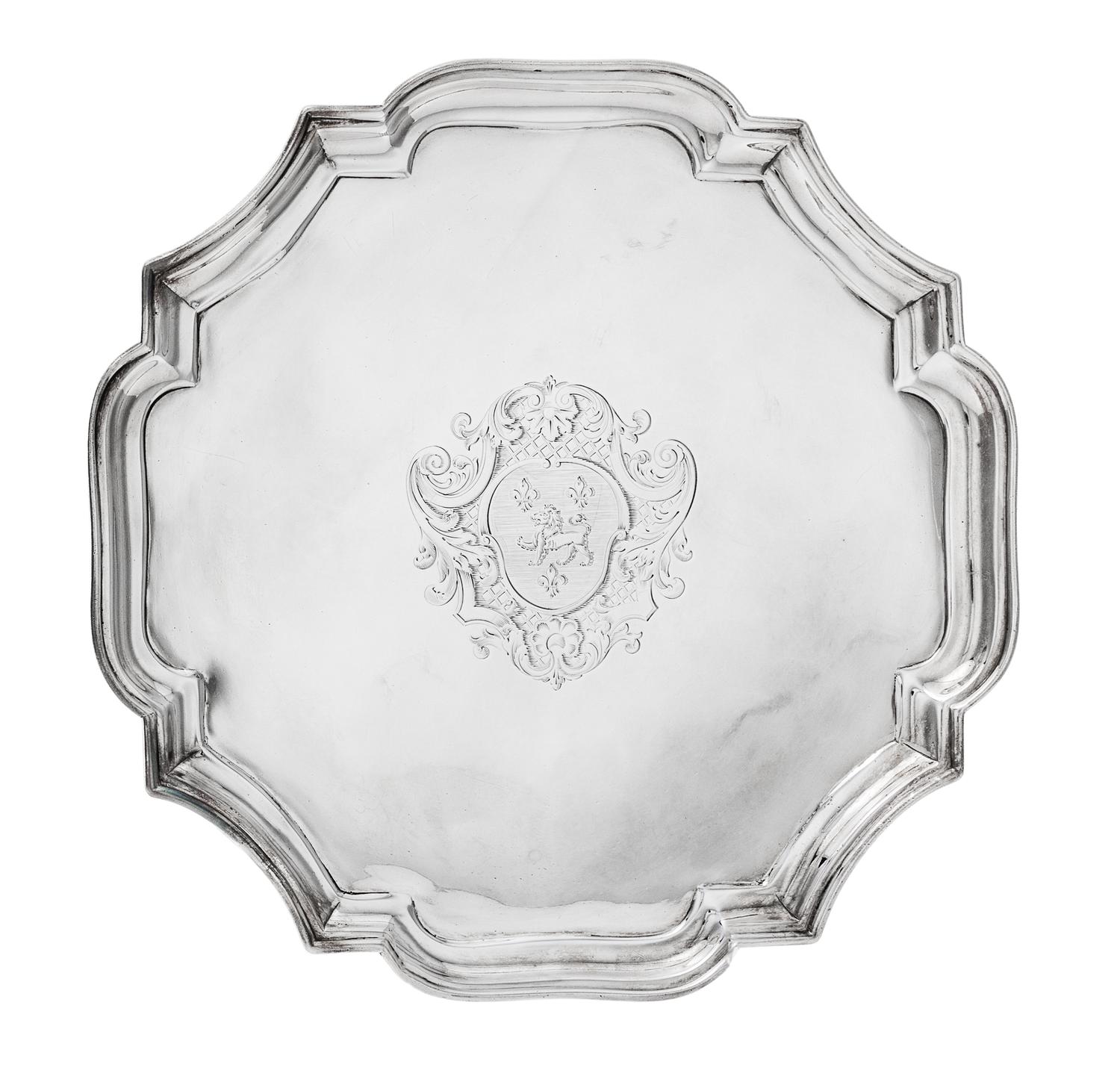 A George I Silver Salver, John Tuite, London, 1727, the piecrust rim centered by an engraved shield crest and raised on four volute fee