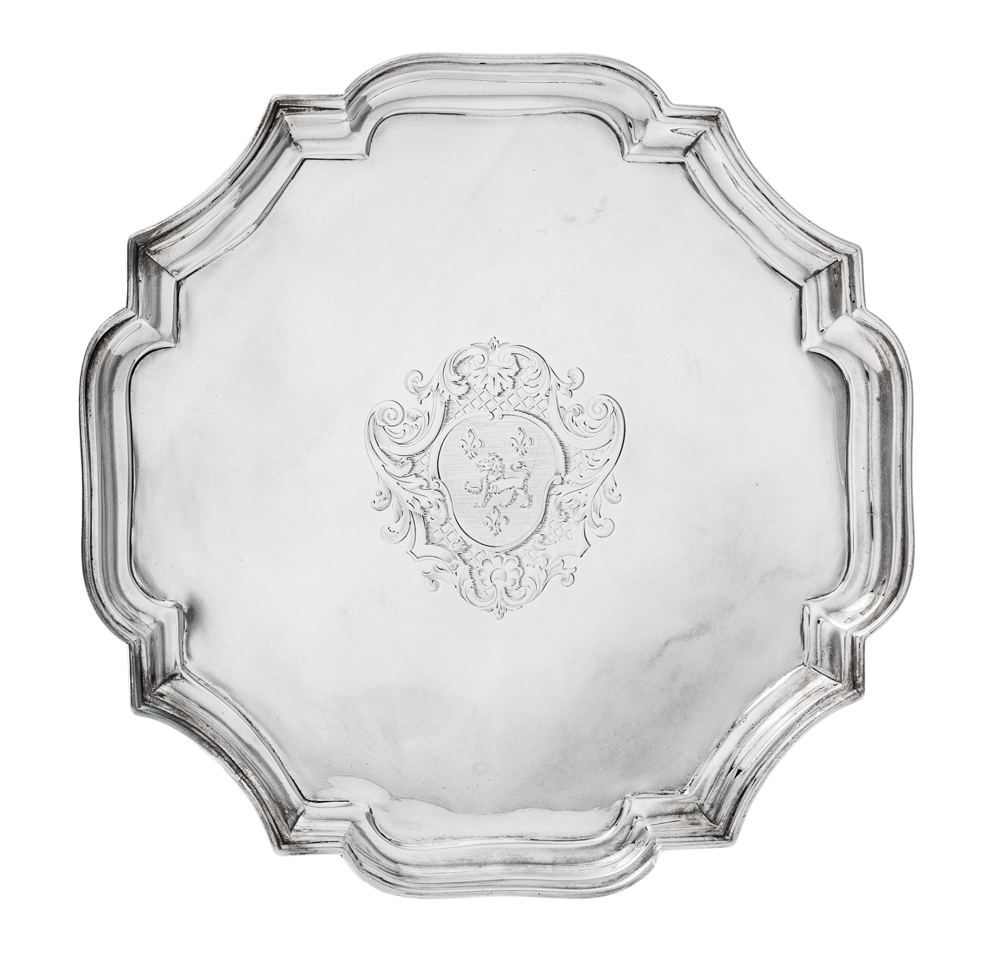 A George I Silver Salver, John Tuite, London, 1727, the piecrust rim centered by an engraved shield crest and raised on four volute fee