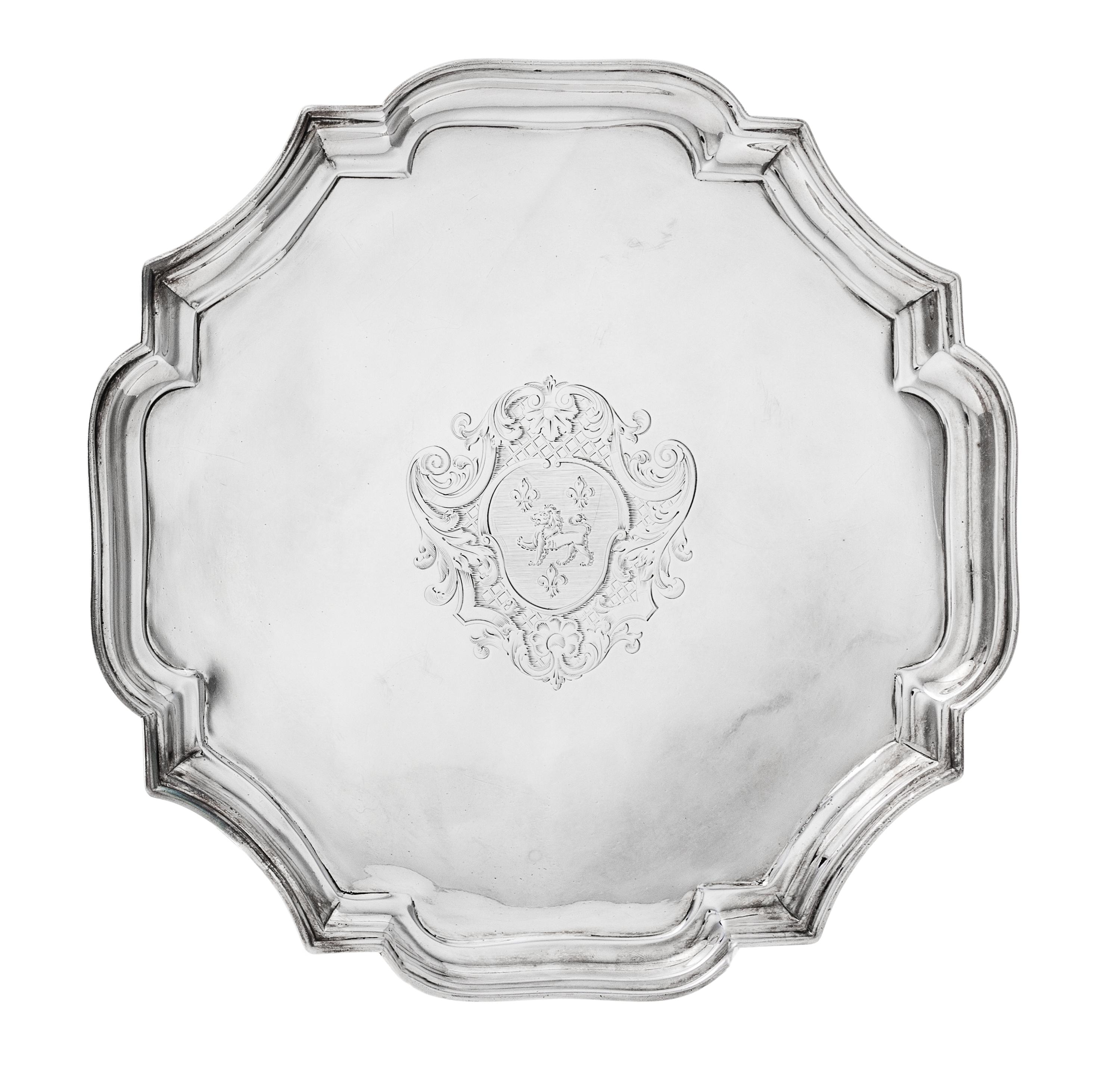 A George I Silver Salver, John Tuite, London, 1727, the piecrust rim centered by an engraved shield crest and raised on four volute fee