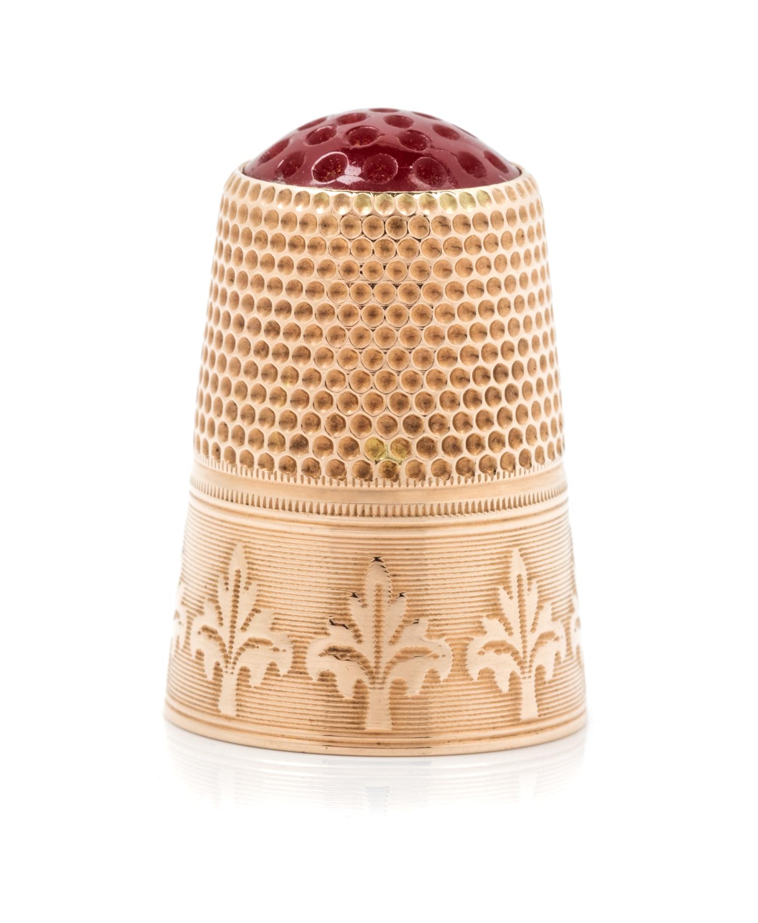 A Continental 12-Karat Gold and Hardstone Thimble, , the hardstone top and knurled body above a foliate decorated band on an engine tur
