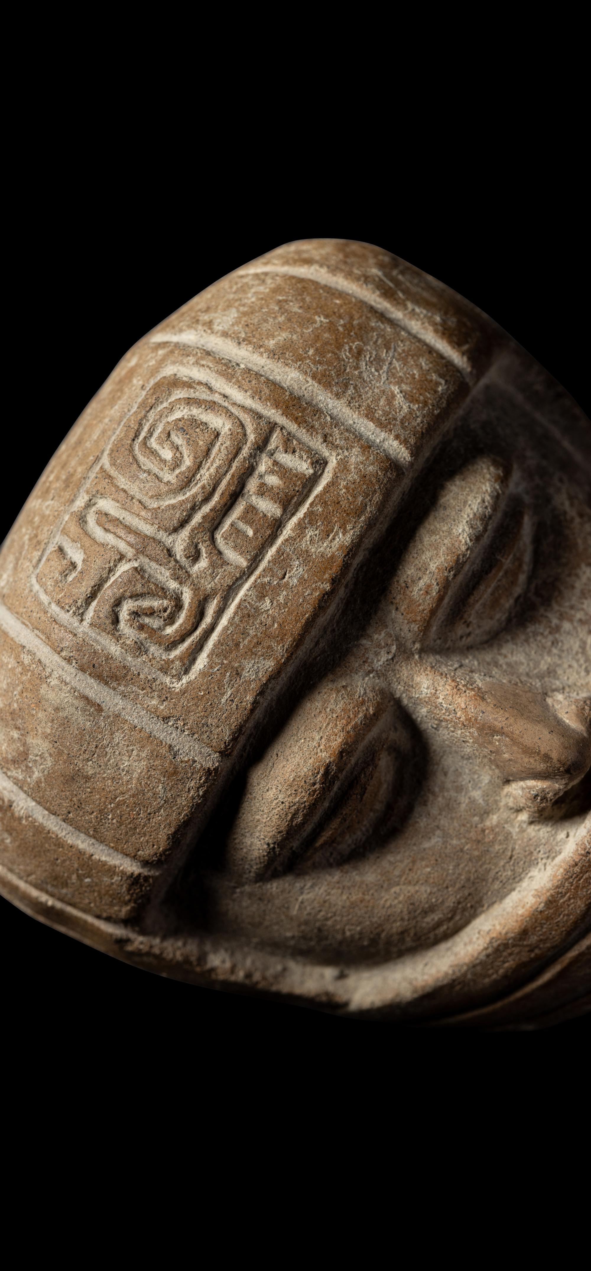 A Veracruz Terracotta Head Wearing a Helmet with an Incised Glyph