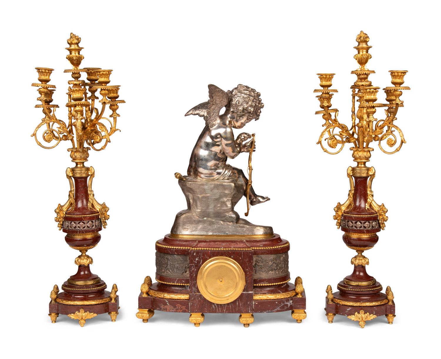 A French Gilt and Silvered Bronze and Rouge Marble Three-Piece Clock Garniture