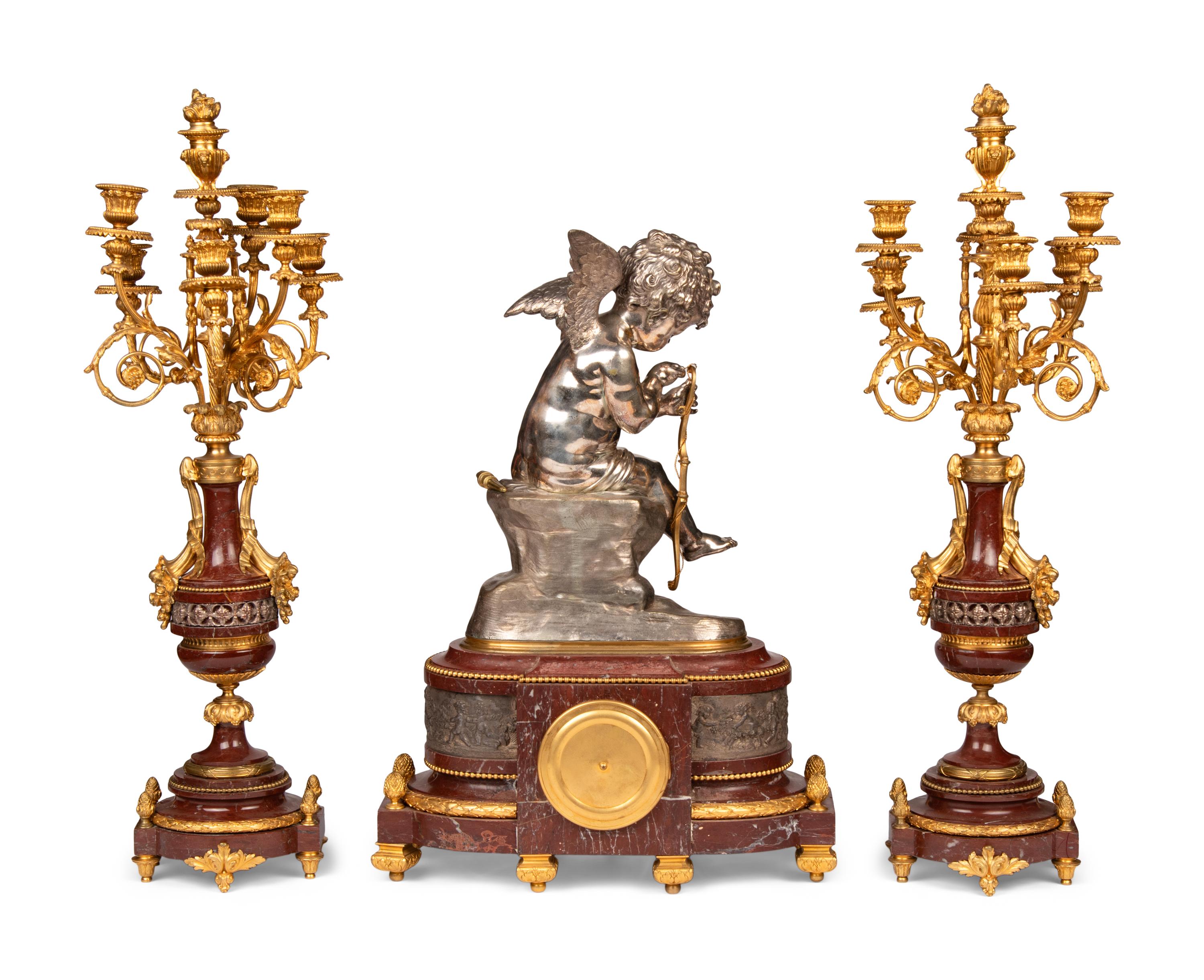 A French Gilt and Silvered Bronze and Rouge Marble Three-Piece Clock Garniture
