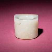 A Chinese Russet and White Jade 'Taotie and Chilong' Archer's Ring, 18th Century — 清中期 白玉留皮饕餮螭龍紋扳指