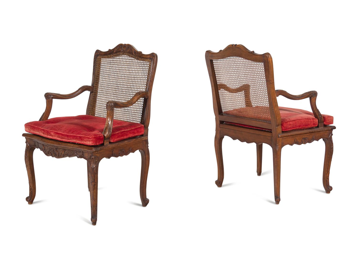 A Pair of Régence Style Carved Walnut and Caned Fauteuils à la Reine