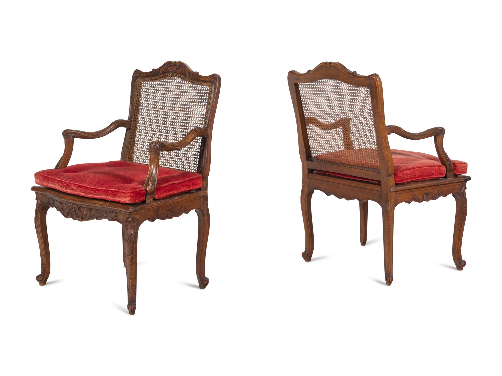 A Pair of Régence Style Carved Walnut and Caned Fauteuils à la Reine