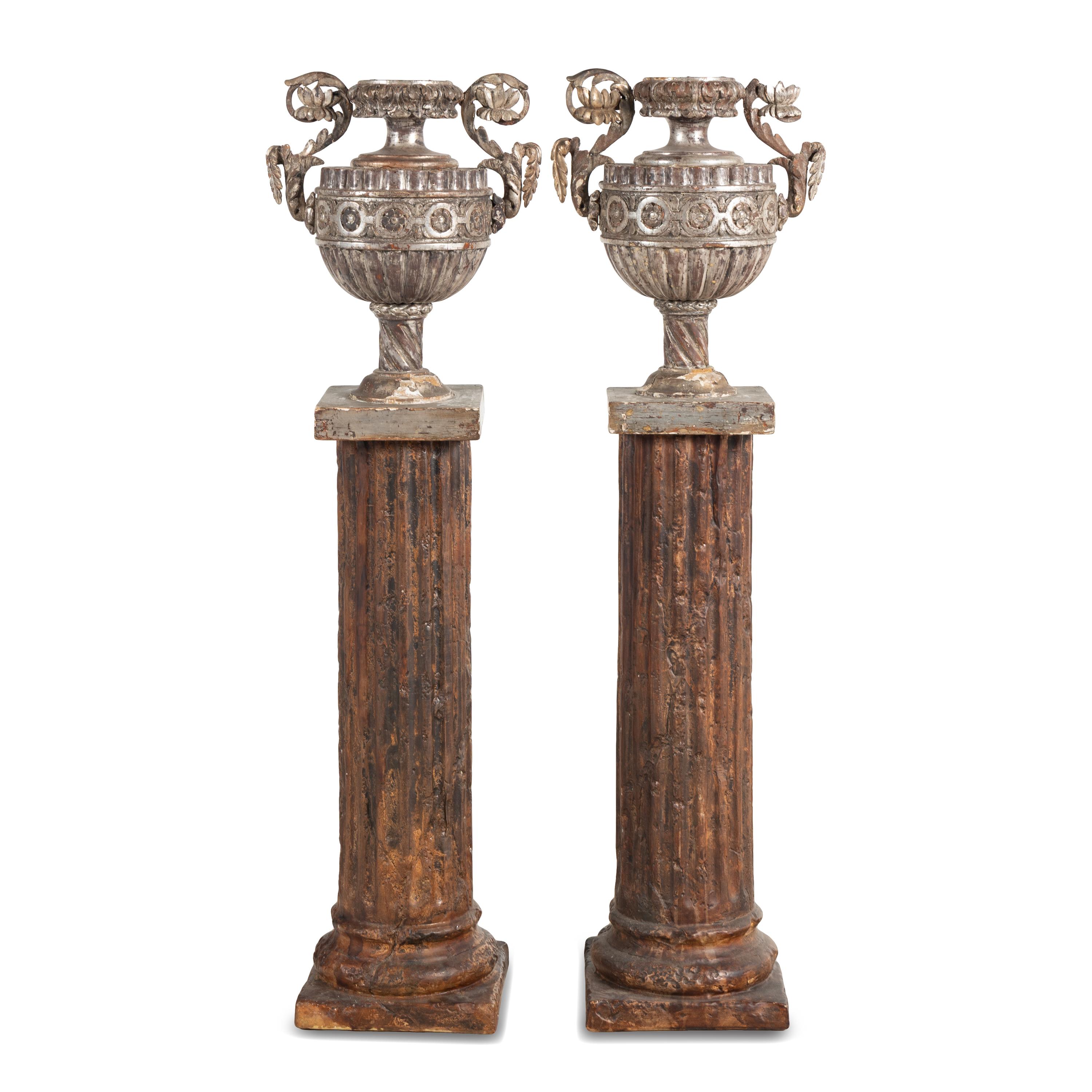 A Pair of Silvered Wood Urn-Form Finials on Painted Columnar Pedestals