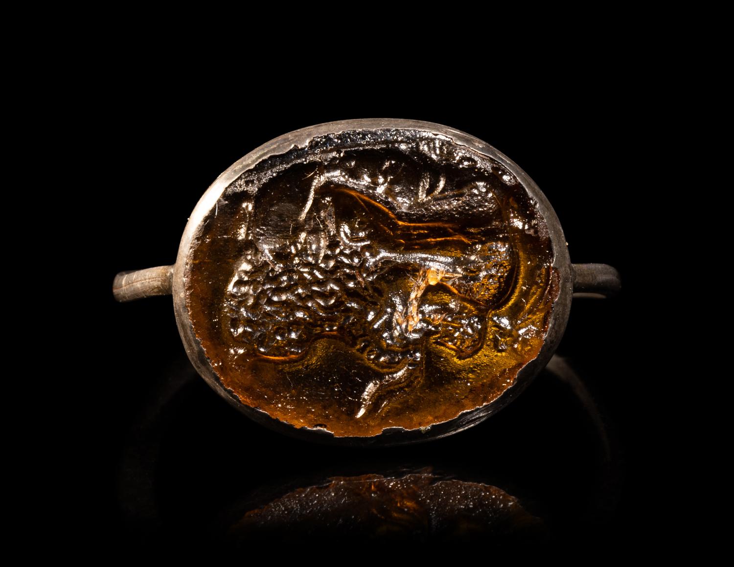 A Roman Silver and Glass Finger Ring of a Satyr Kissing a Goat