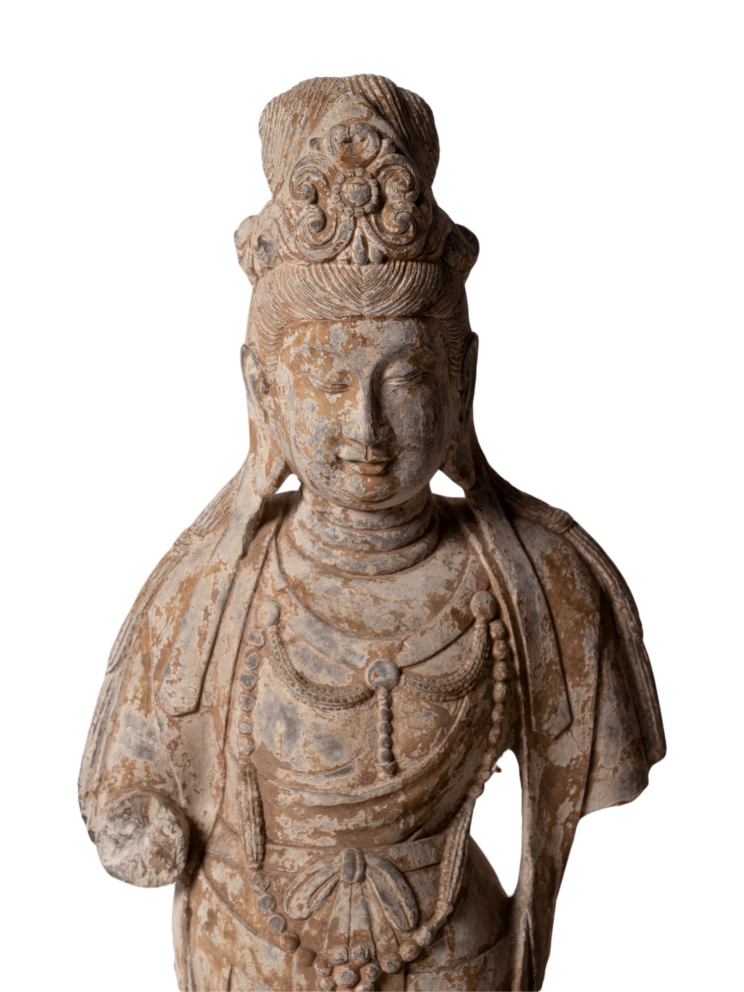 A Chinese Carved Stone Standing Guanyin Figure with Remnants of Polychrome Decoration