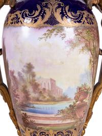 A Pair of Sèvres Style Gilt Bronze Mounted Painted and Parcel Gilt Porcelain Urns