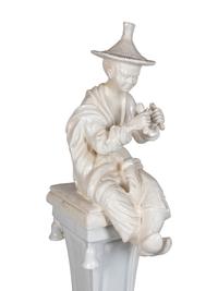 A Continental Blanc de Chine Figure of a Seated Chinese Man on a Pedestal
