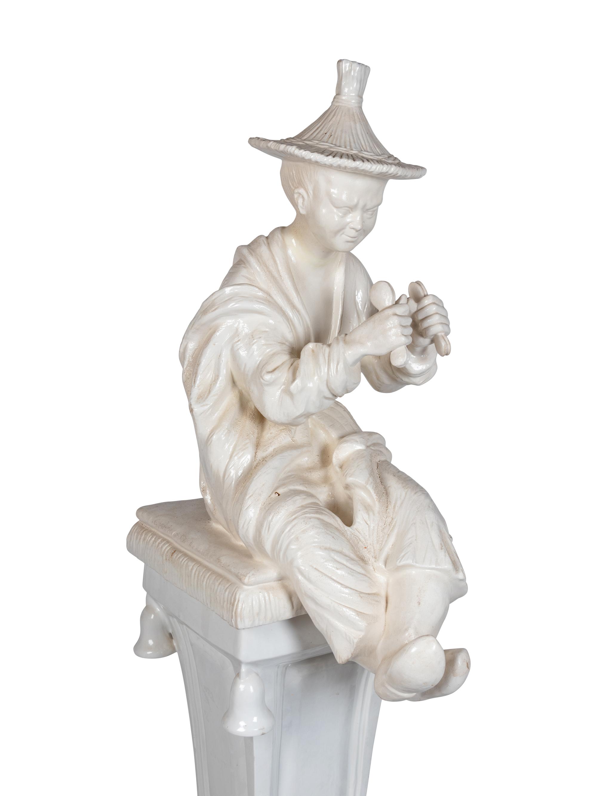 A Continental Blanc de Chine Figure of a Seated Chinese Man on a Pedestal