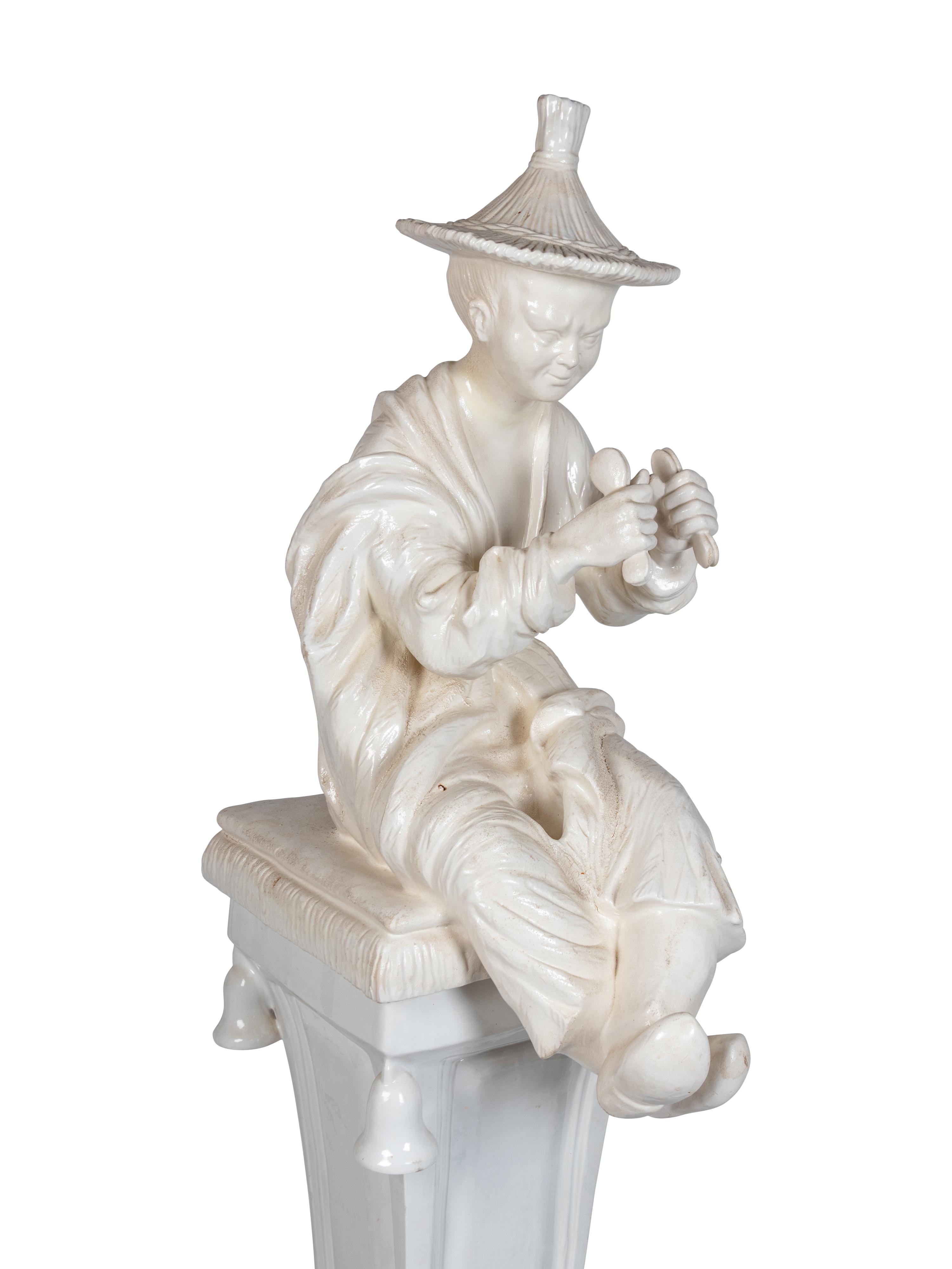 A Continental Blanc de Chine Figure of a Seated Chinese Man on a Pedestal