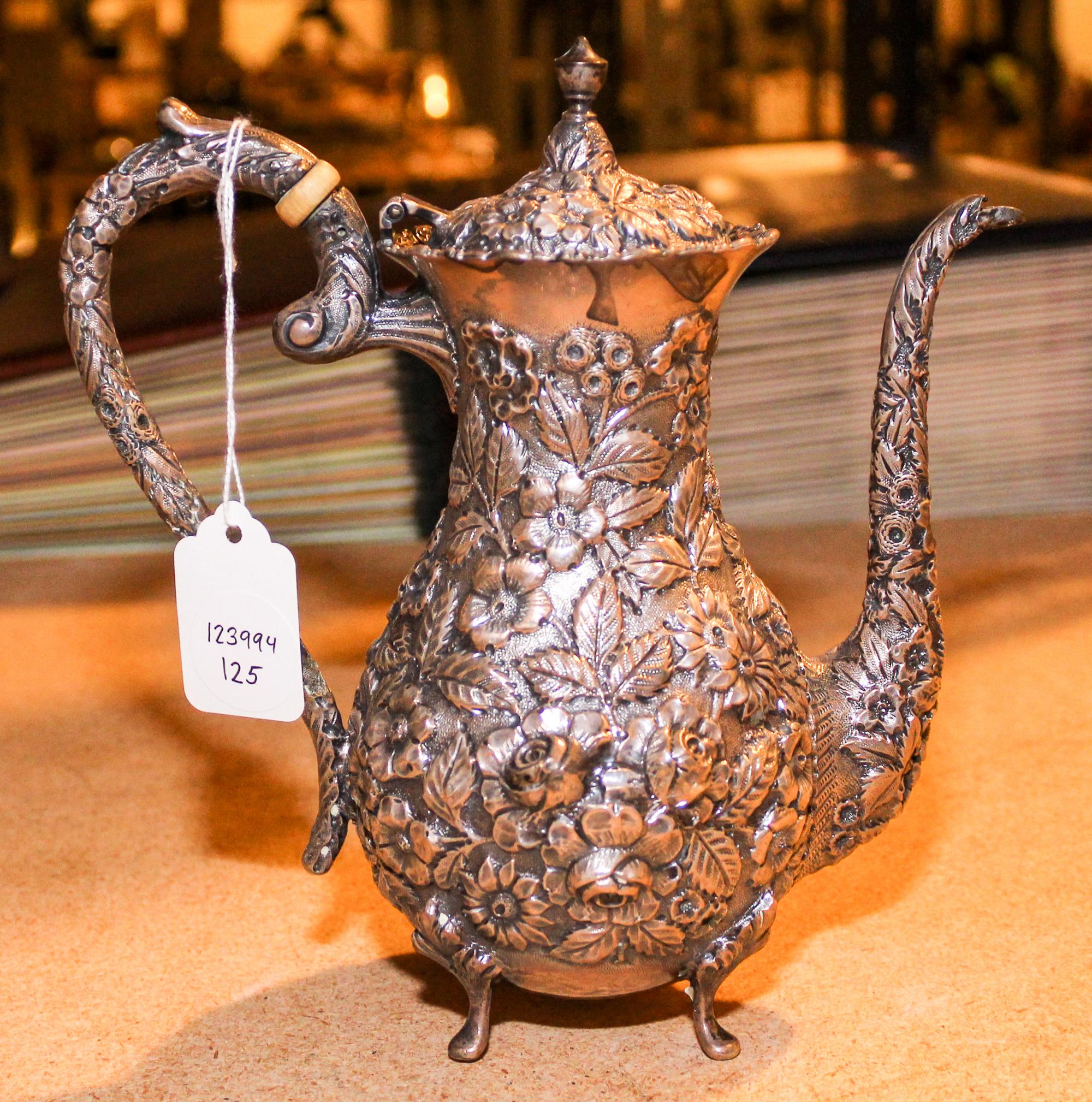 An American Silver Teapot, Baltimore Silversmiths Mfg. Co., having an urn finial, the body decorated with floral and foliate repousse d