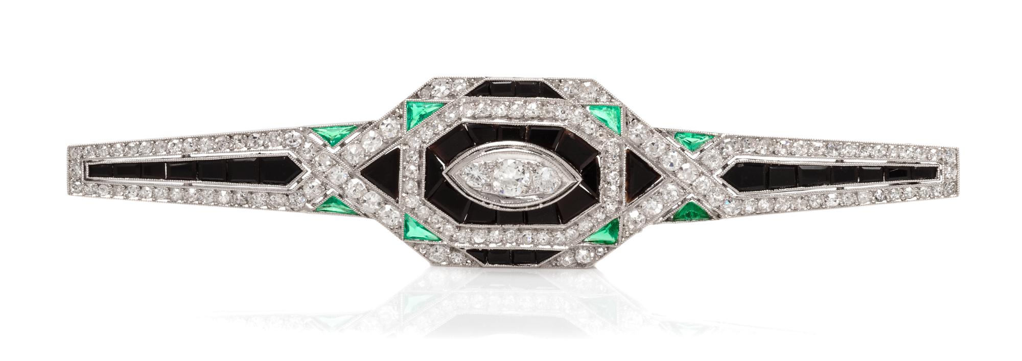 An Art Deco Platinum, Diamond, Onyx and Emerald Bar Brooch, French, 7.40 dwts.