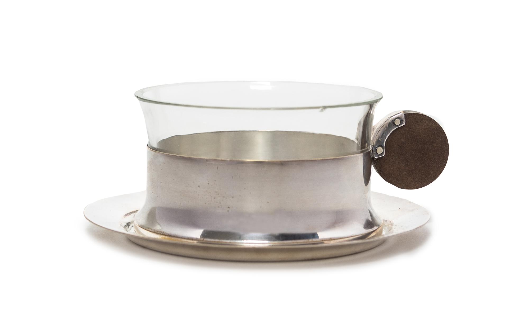 A German Art Deco Silver-plate and Glass Teacup and Saucer Diameter of saucer 5 1/8 inches.