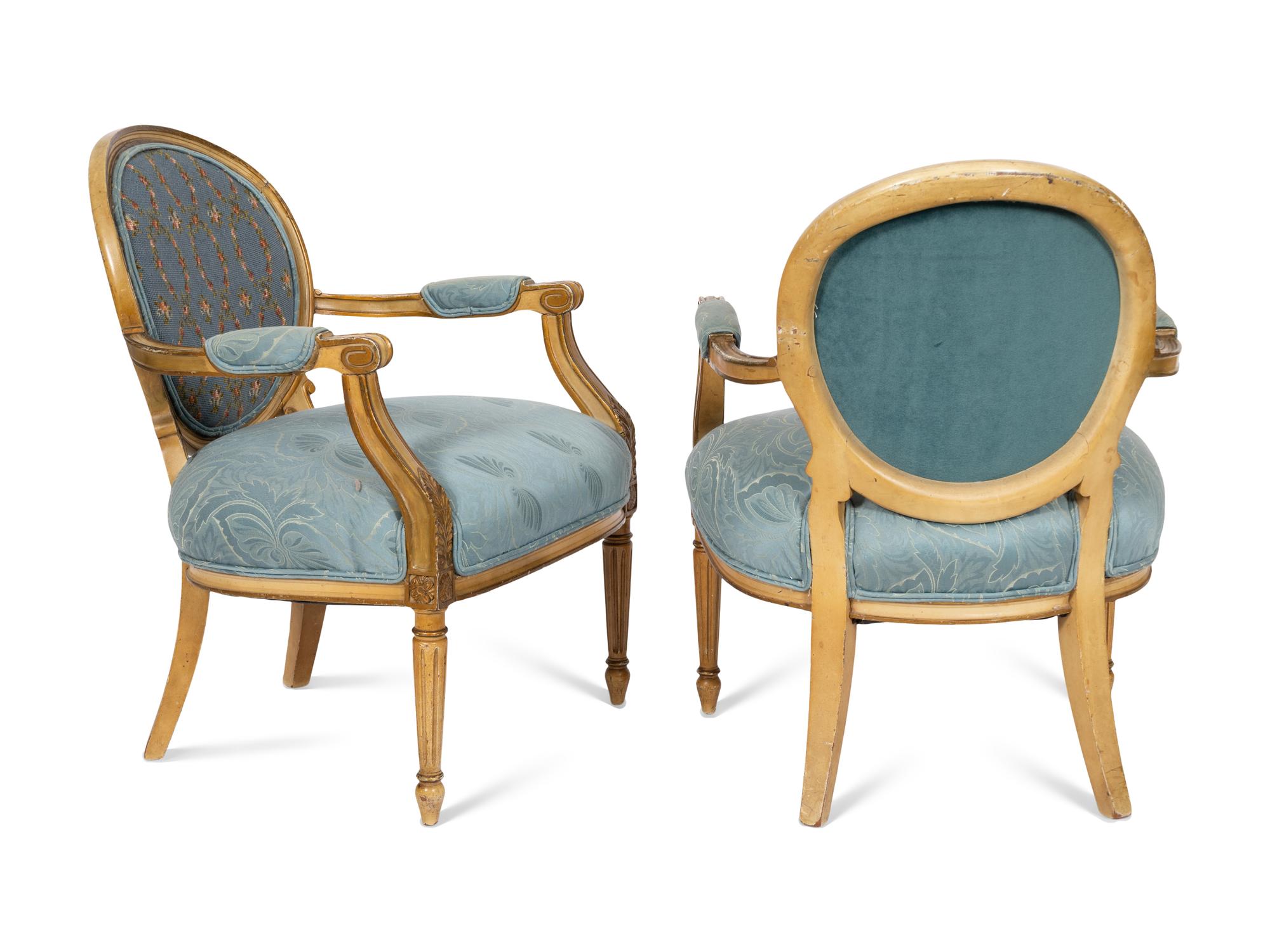 A Pair of Louis XVI Style Cream-Painted and Parcel Gilt Fauteuils with Needlepoint Backs