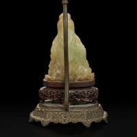 A Chinese carved mottled celadon jade figure of Guanyin, mounted as a lamp 玉雕观音改装台灯