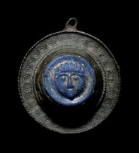 A Romano-Celtic Bronze and Blue Glass Fibula with a Mask