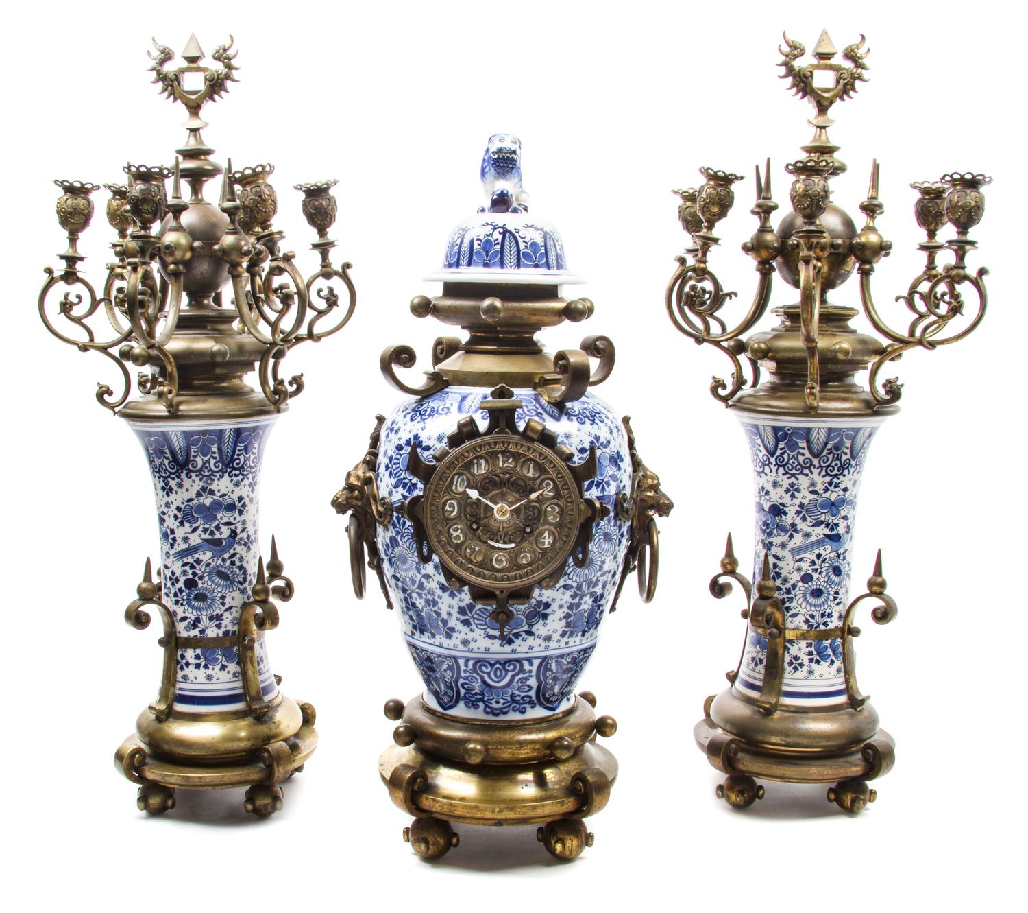 A Gilt Metal and Delft Pottery Clock Garniture Height of tallest 28 1/2 inches. — MOVEMENT BY H.L. LUPPENS