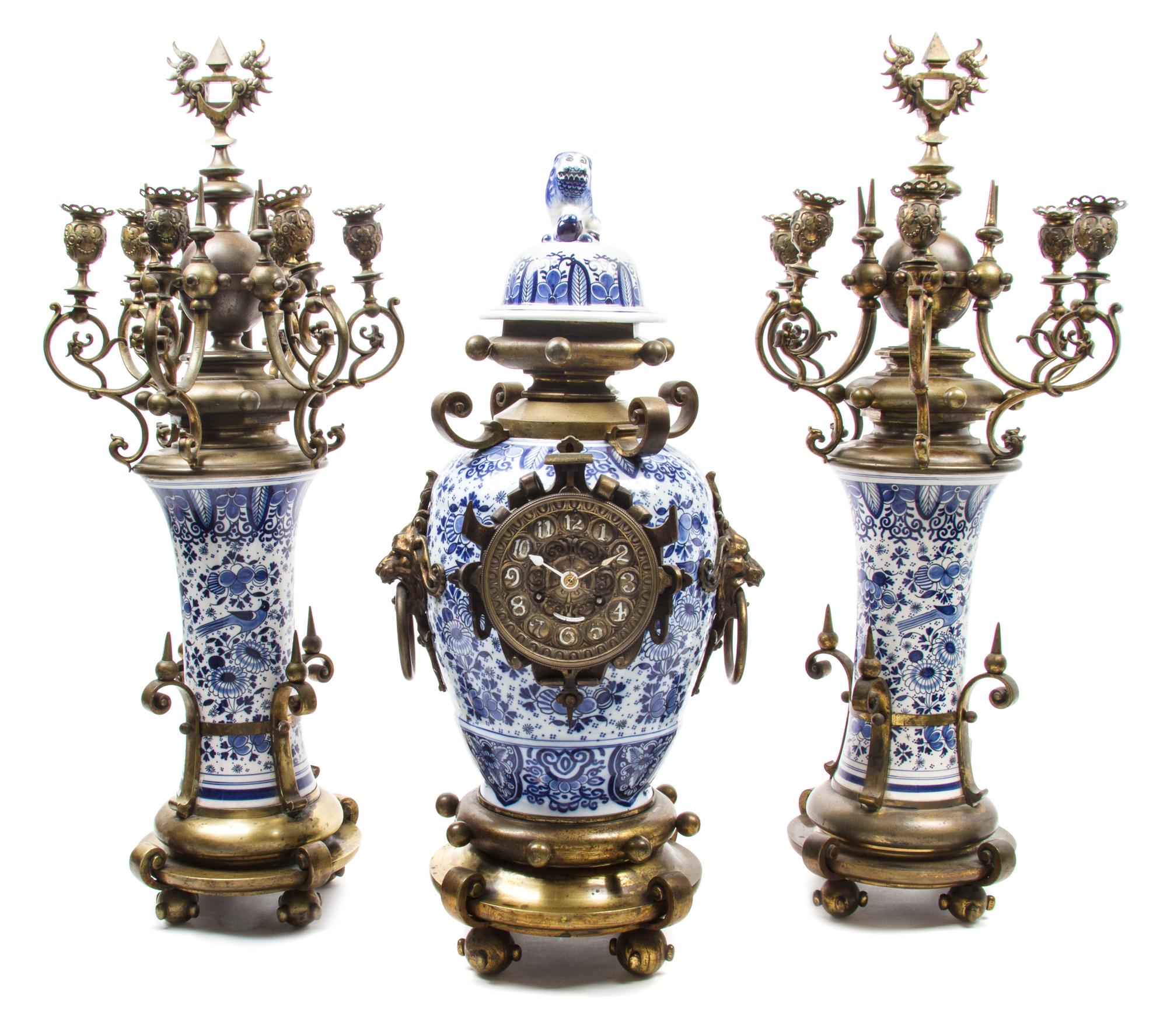 A Gilt Metal and Delft Pottery Clock Garniture Height of tallest 28 1/2 inches. — MOVEMENT BY H.L. LUPPENS