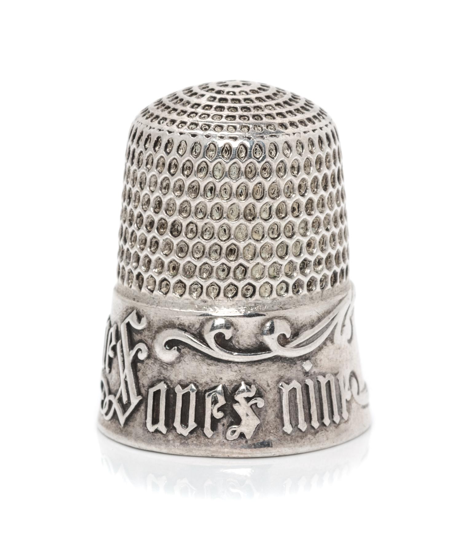 An American Silver Thimble, Simons Bros., Philadelphia, PA, the based marked A Stitch in Time Saves Nine with a vacant cartouche framed