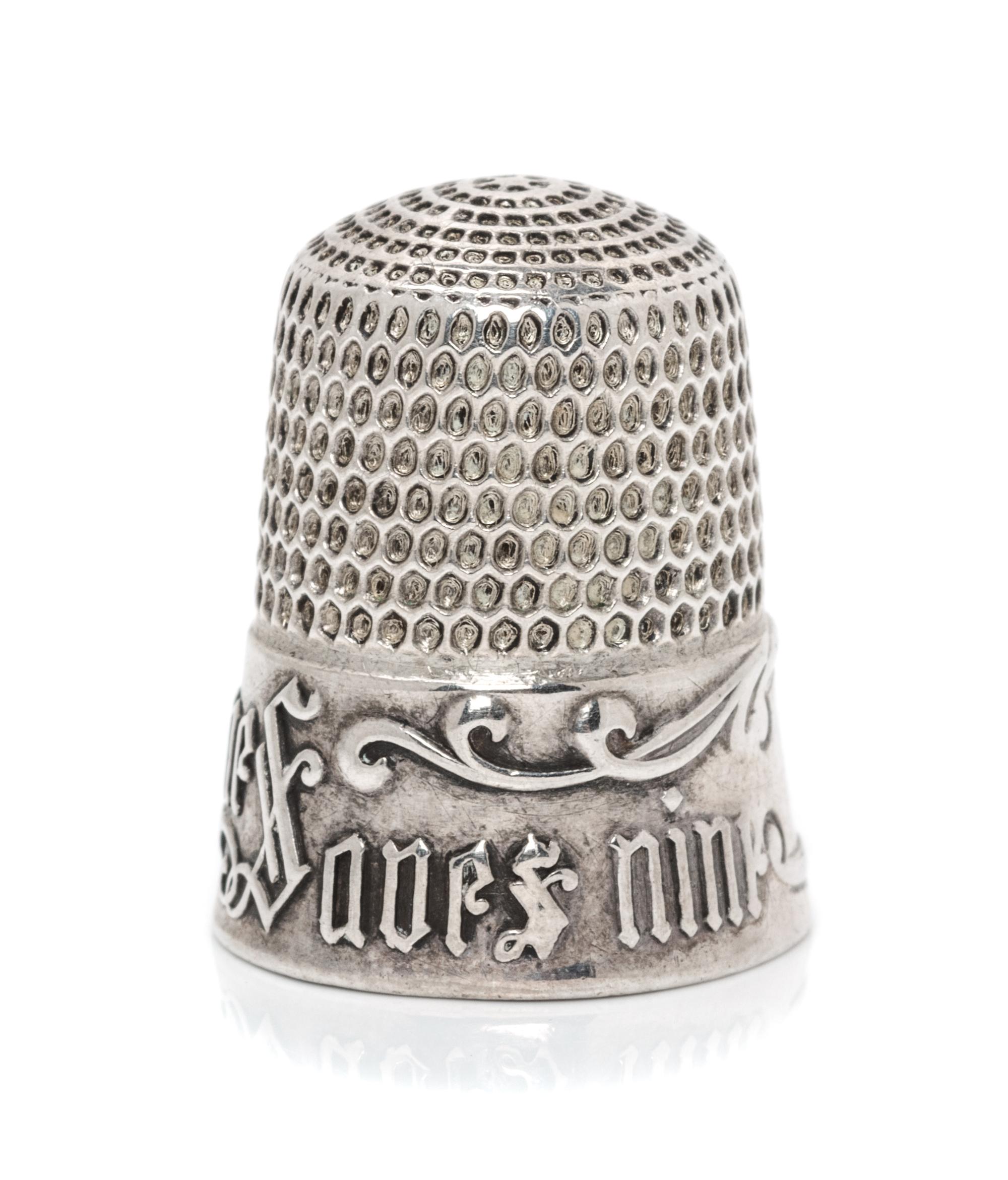 An American Silver Thimble, Simons Bros., Philadelphia, PA, the based marked A Stitch in Time Saves Nine with a vacant cartouche framed