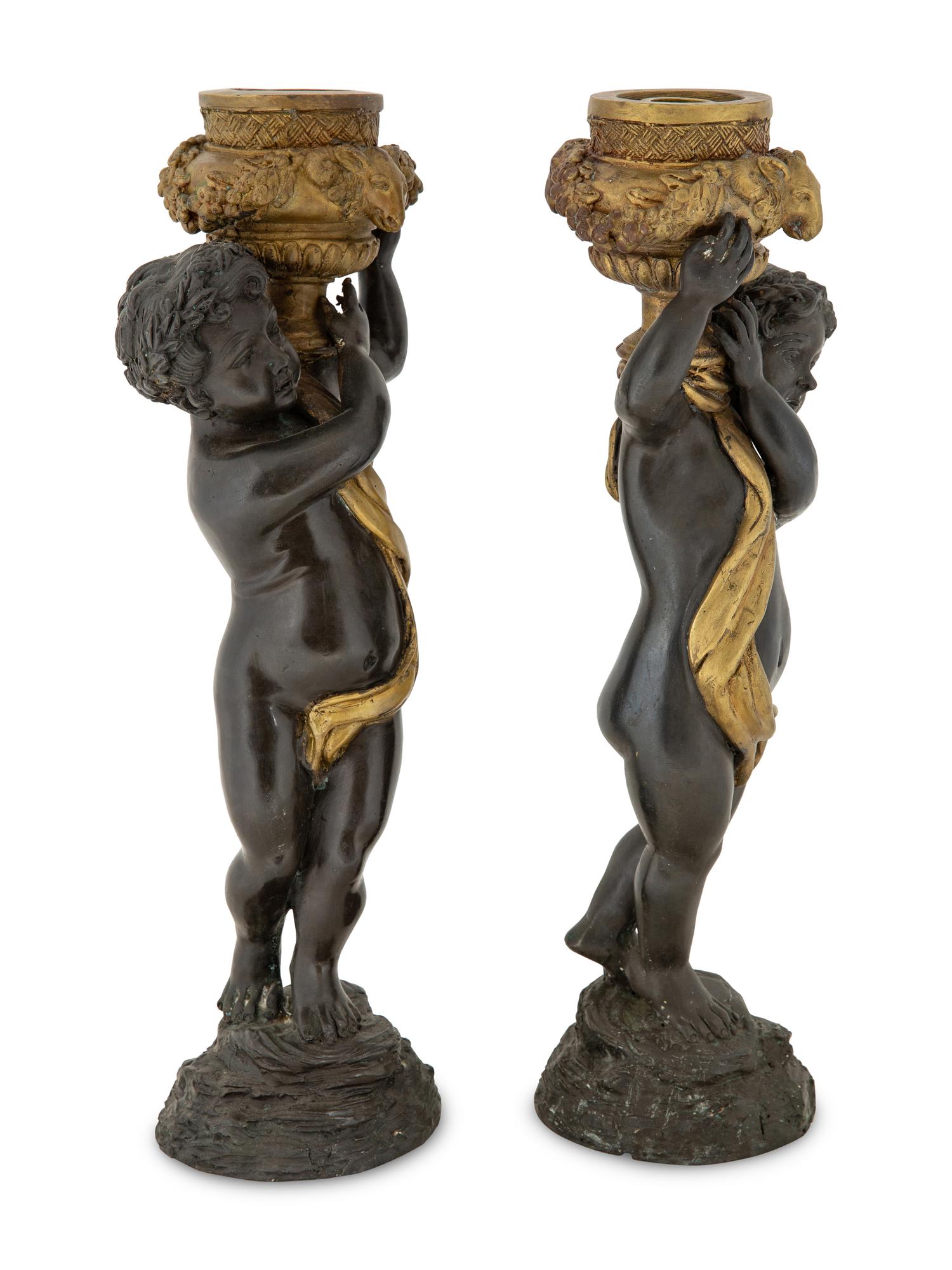 A Pair of Parcel Gilt Cast Metal Putti Candlesticks