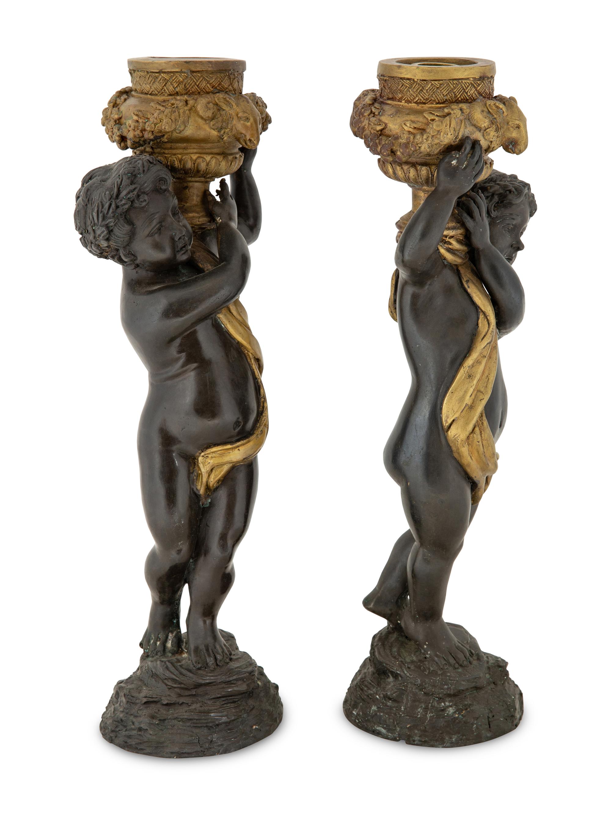 A Pair of Parcel Gilt Cast Metal Putti Candlesticks