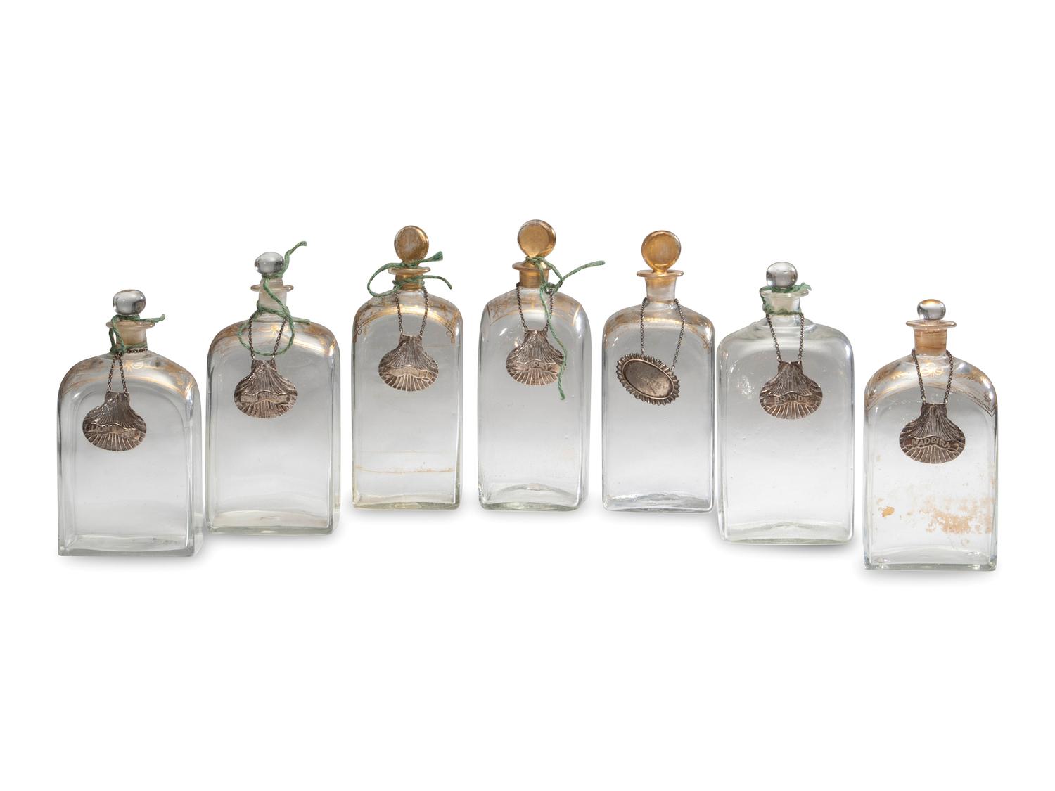 Fifteen Glass Decanters with English Shell-Form Silver Bottle Tags
