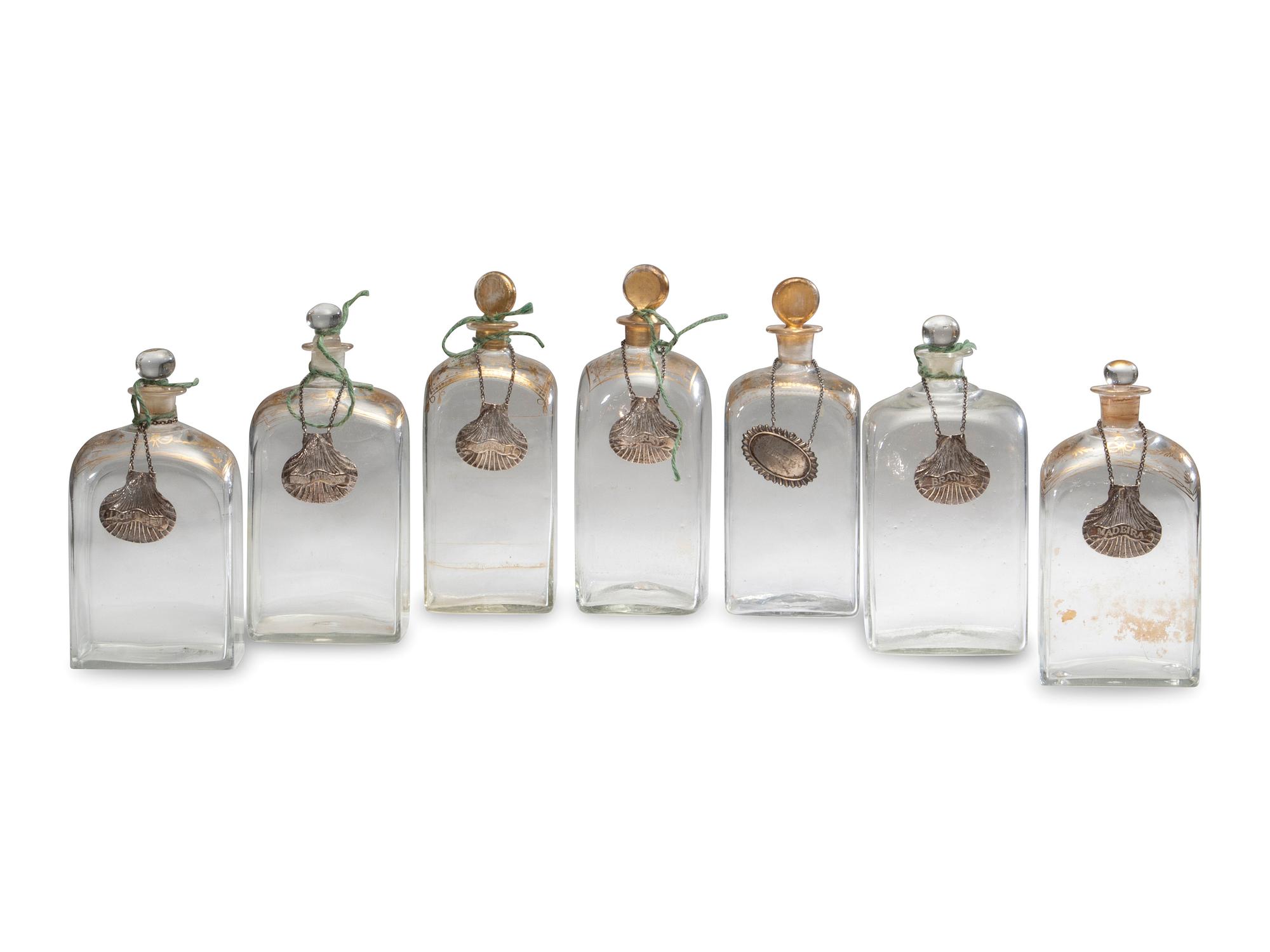 Fifteen Glass Decanters with English Shell-Form Silver Bottle Tags