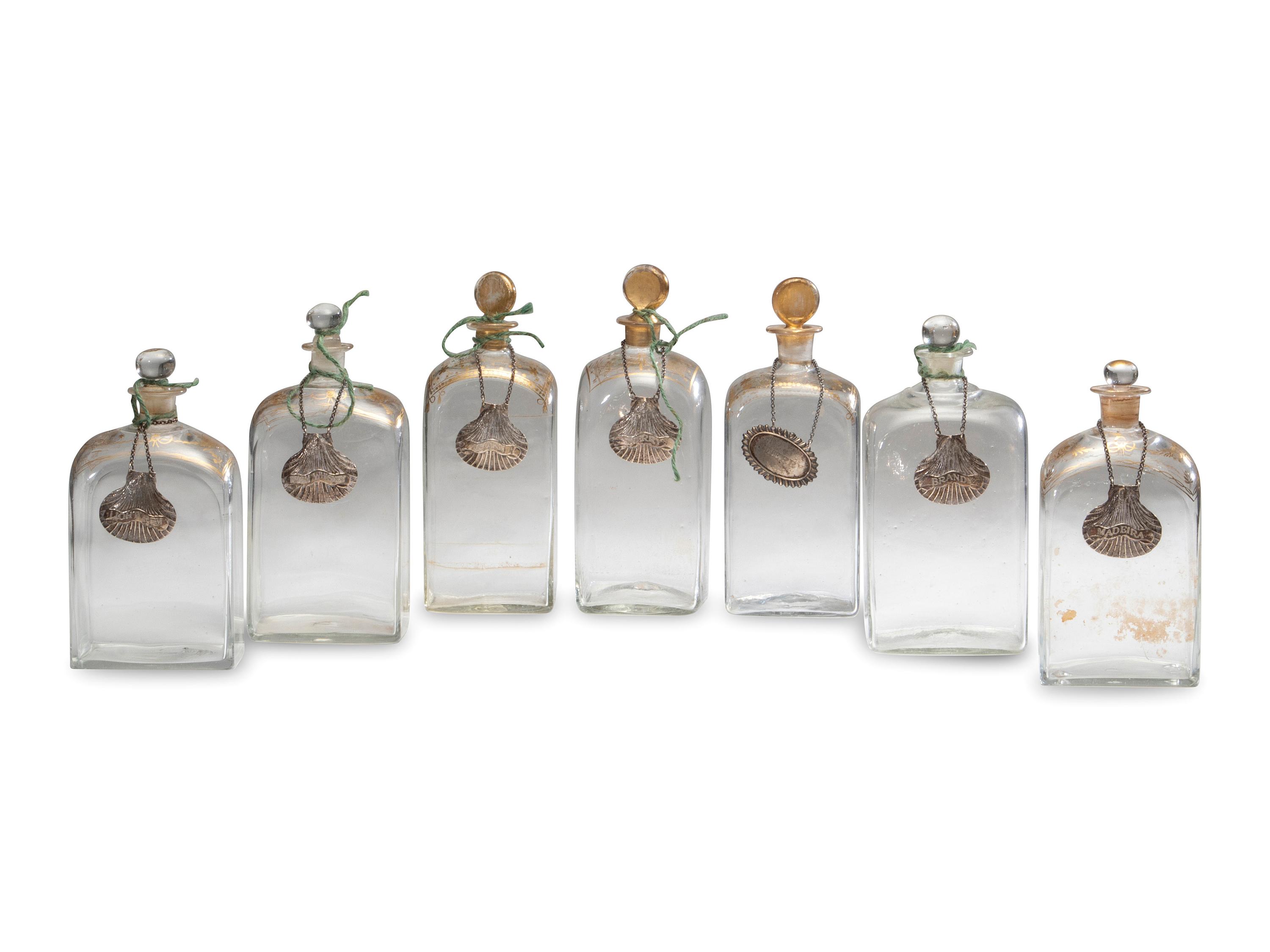 Fifteen Glass Decanters with English Shell-Form Silver Bottle Tags