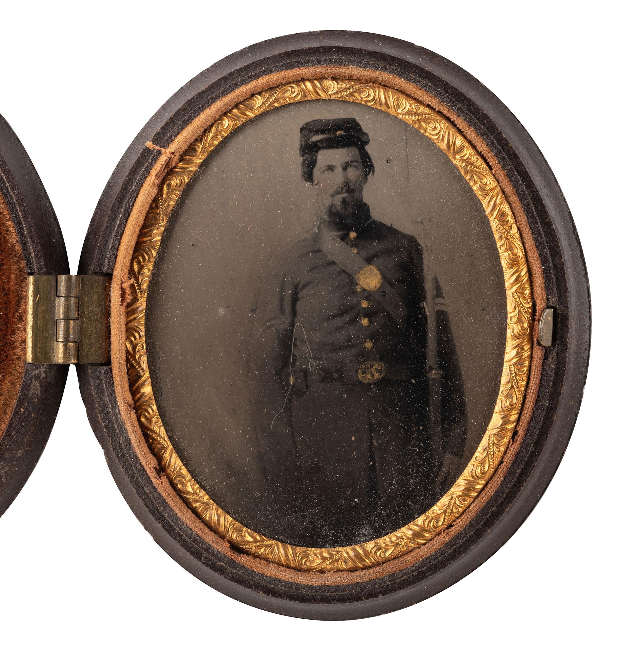 [CIVIL WAR]. CDV-sized tintype of a Union cavalryman posed against a military camp background.