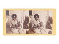 [African Americana]. Stereoview of an African American woman and a white child seated on a front porch.