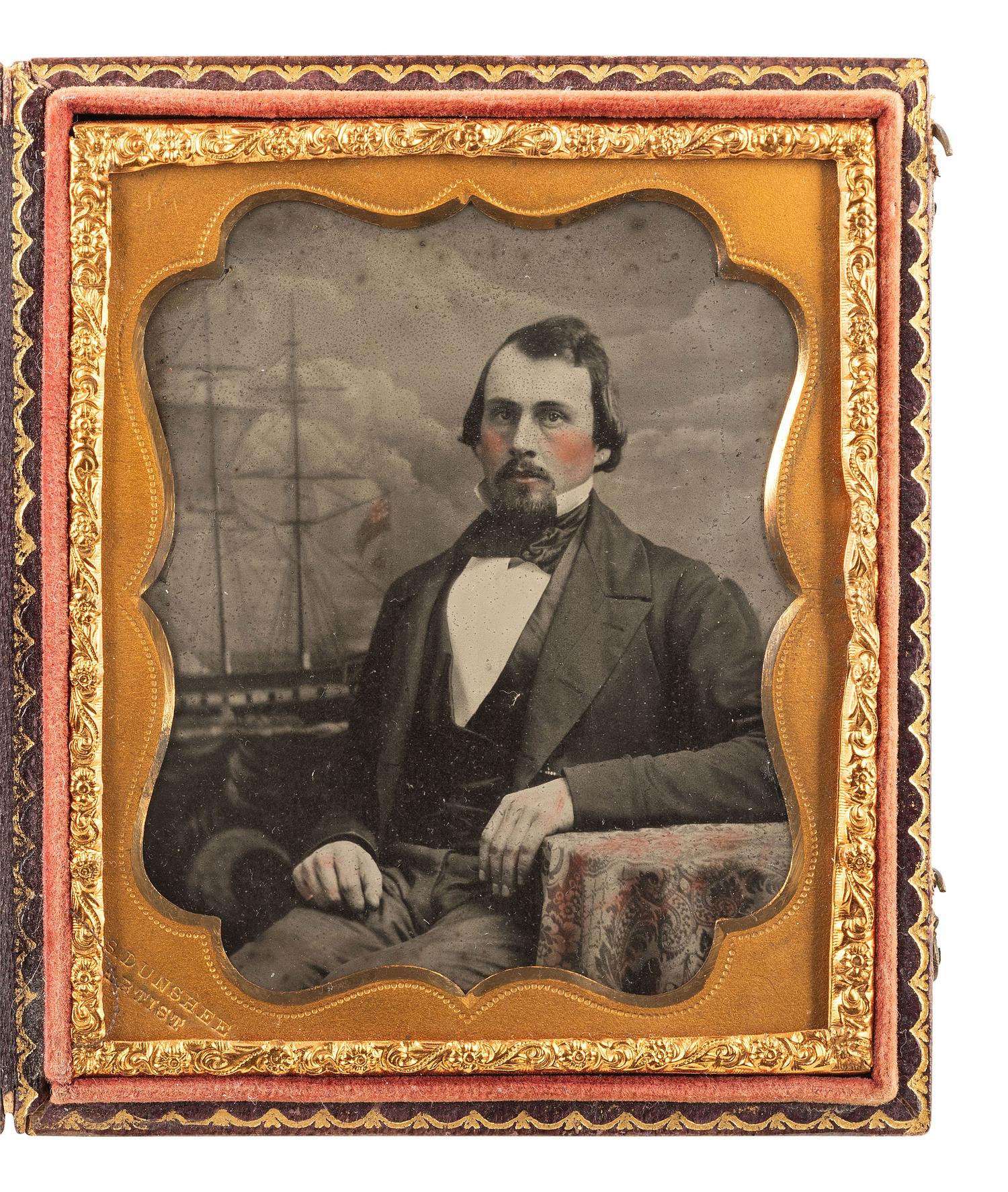[EARLY PHOTOGRAPHY]. DUNSHEE, S., photographer. Sixth plate ambrotype of a gentleman posed before a painting of a British ship.