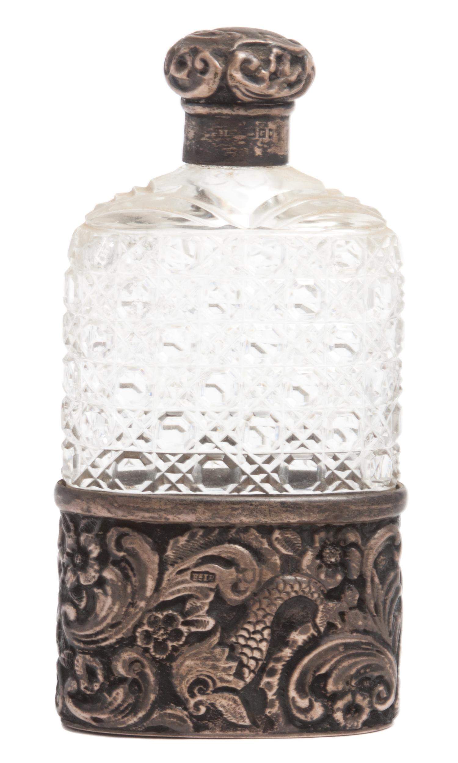 An English Silver Mounted Hip Flask, Finnigans Ltd., Manchester, having a cut glass bottle mounted in a silver base with silver top.