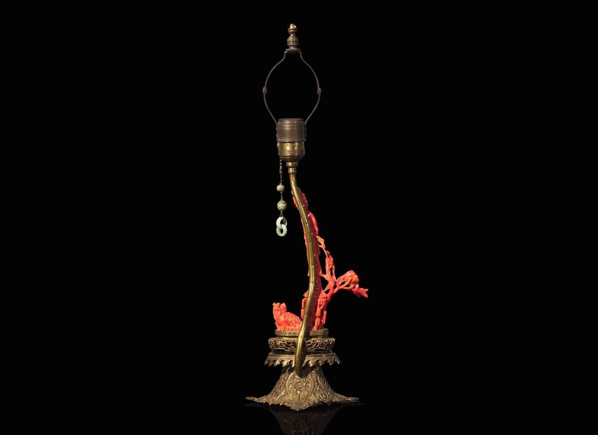 A Chinese carved coral figure mounted on a gilt-metal lamp base 珊瑚雕人物嵌銅鎏金燈座