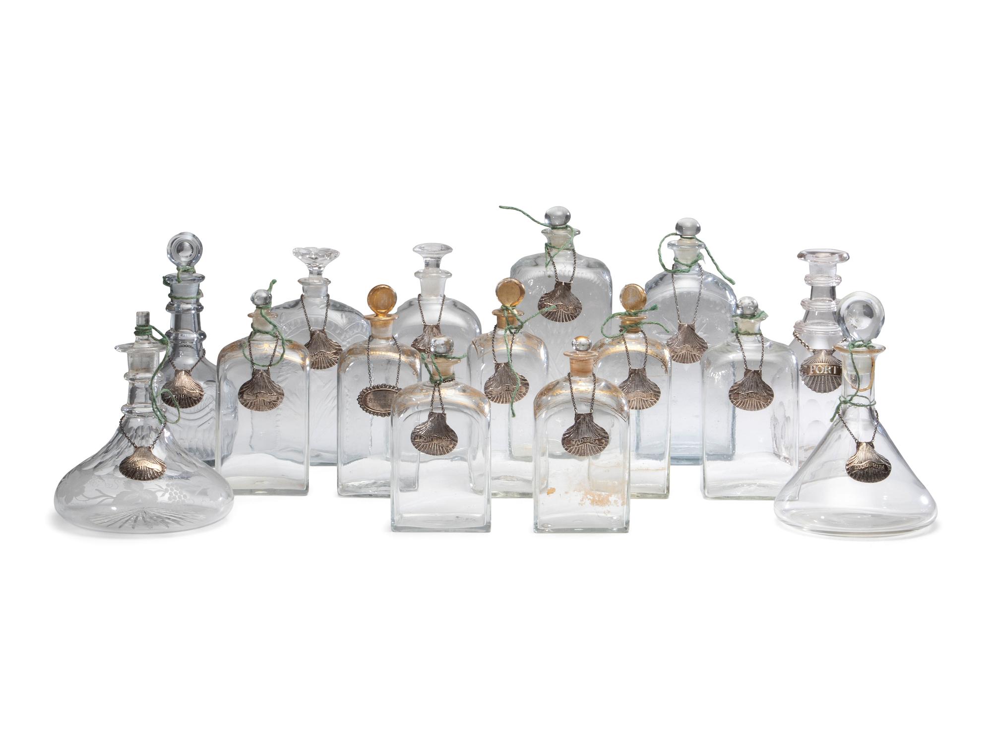 Fifteen Glass Decanters with English Shell-Form Silver Bottle Tags