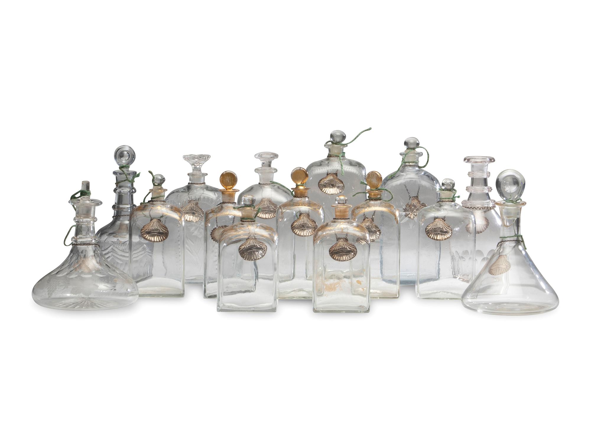 Fifteen Glass Decanters with English Shell-Form Silver Bottle Tags