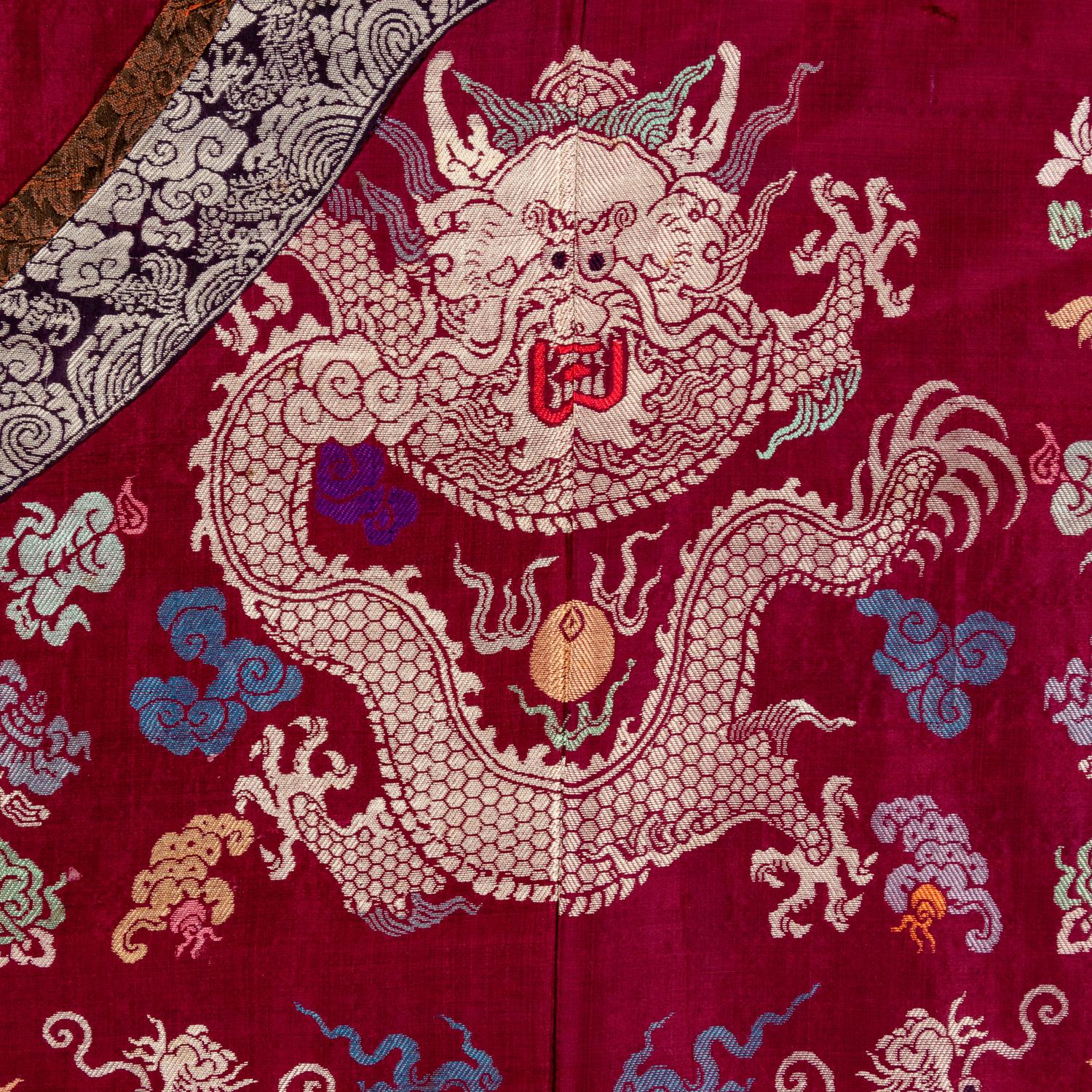 A Chinese Maroon Ground Silk Brocade 'Dragon' Robe, Jifu, Late Qing Dynasty 清晚期 絳紅地織錦龍紋吉服