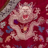 A Chinese Maroon Ground Silk Brocade 'Dragon' Robe, Jifu, Late Qing Dynasty 清晚期 絳紅地織錦龍紋吉服