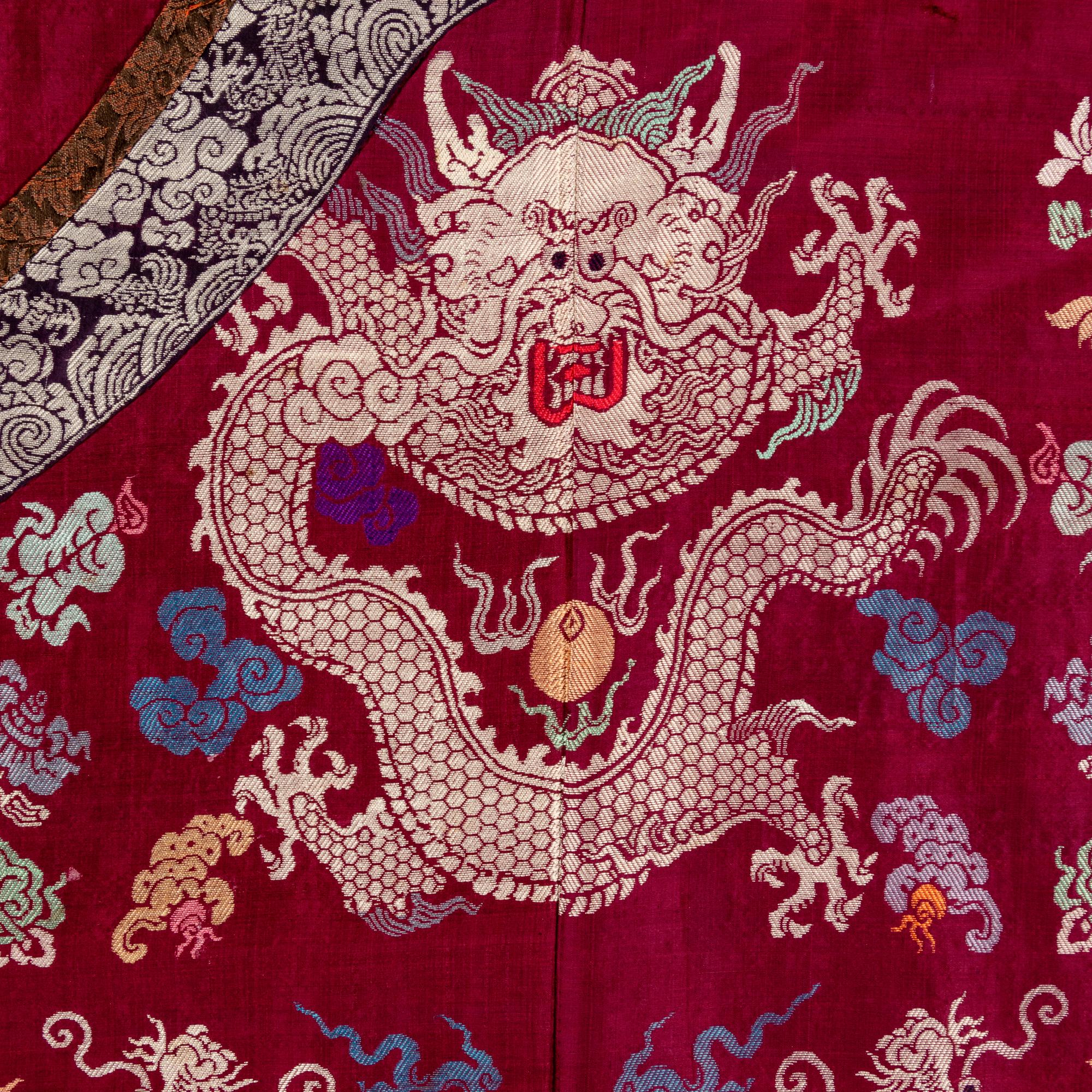 A Chinese Maroon Ground Silk Brocade 'Dragon' Robe, Jifu, Late Qing Dynasty 清晚期 絳紅地織錦龍紋吉服