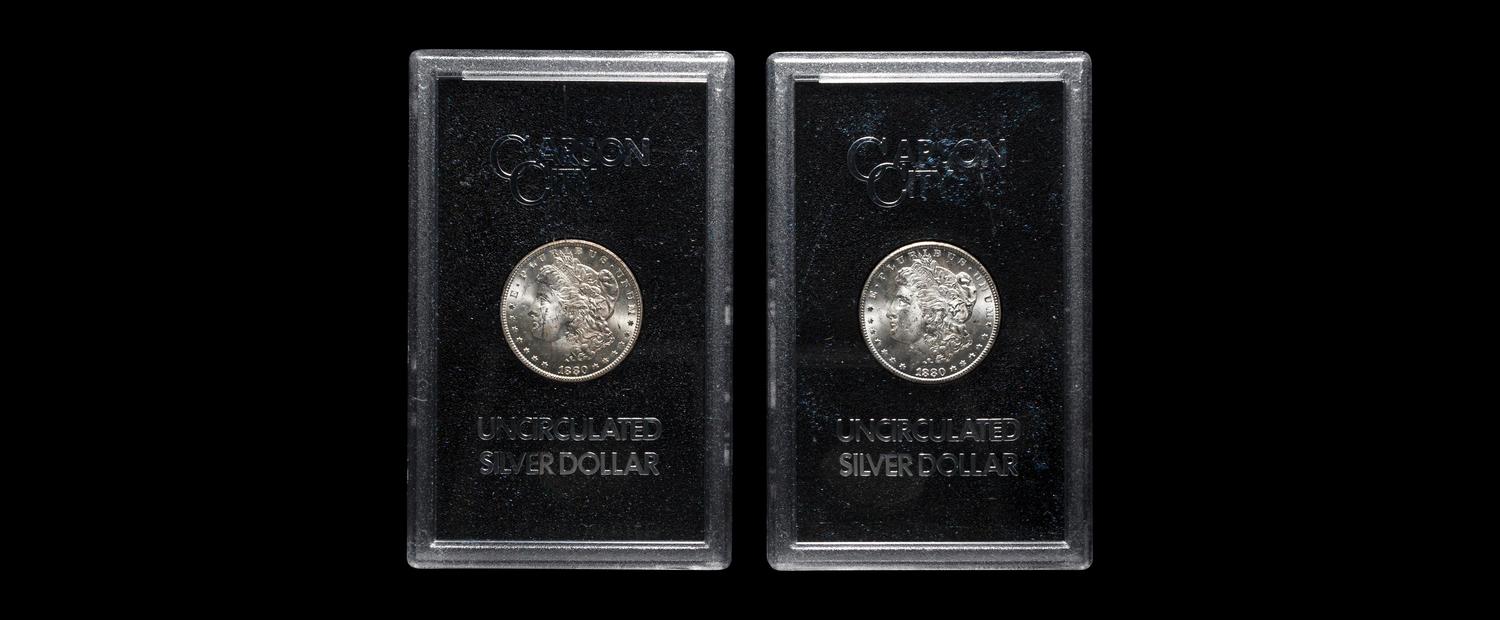 A Group of Two 1880-CC GSA: Morgan $1 Coins