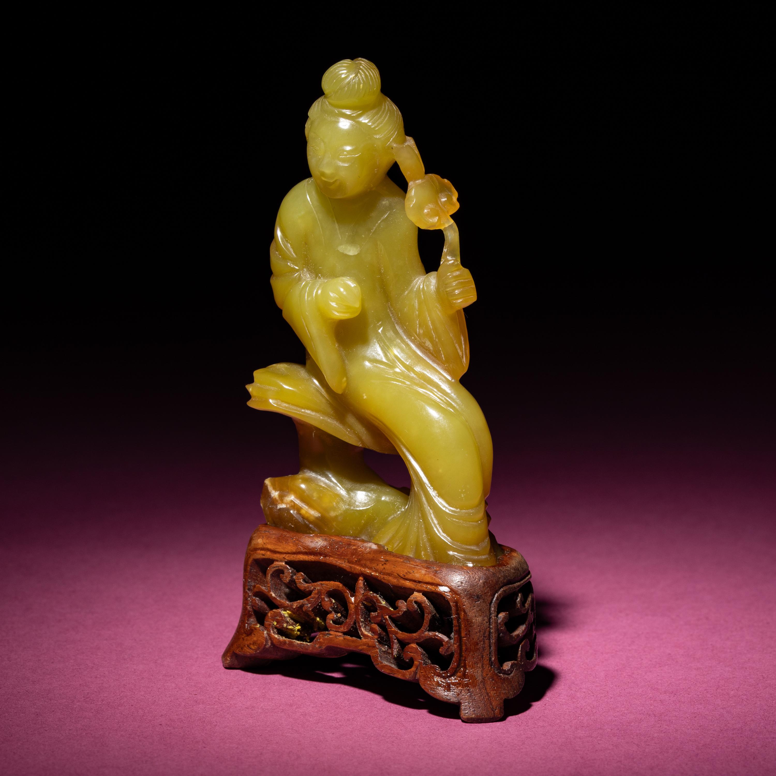 A Chinese Yellow Jade Seated Figure of a Lady, Late Qing Dynasty — 清晚期 黃玉持蓮仕女