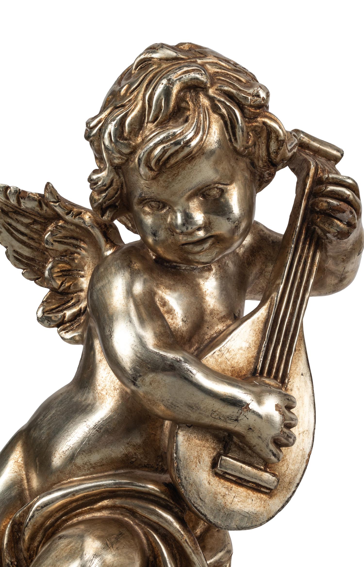 A Pair of Silvered Wood Musical Putto Ornaments