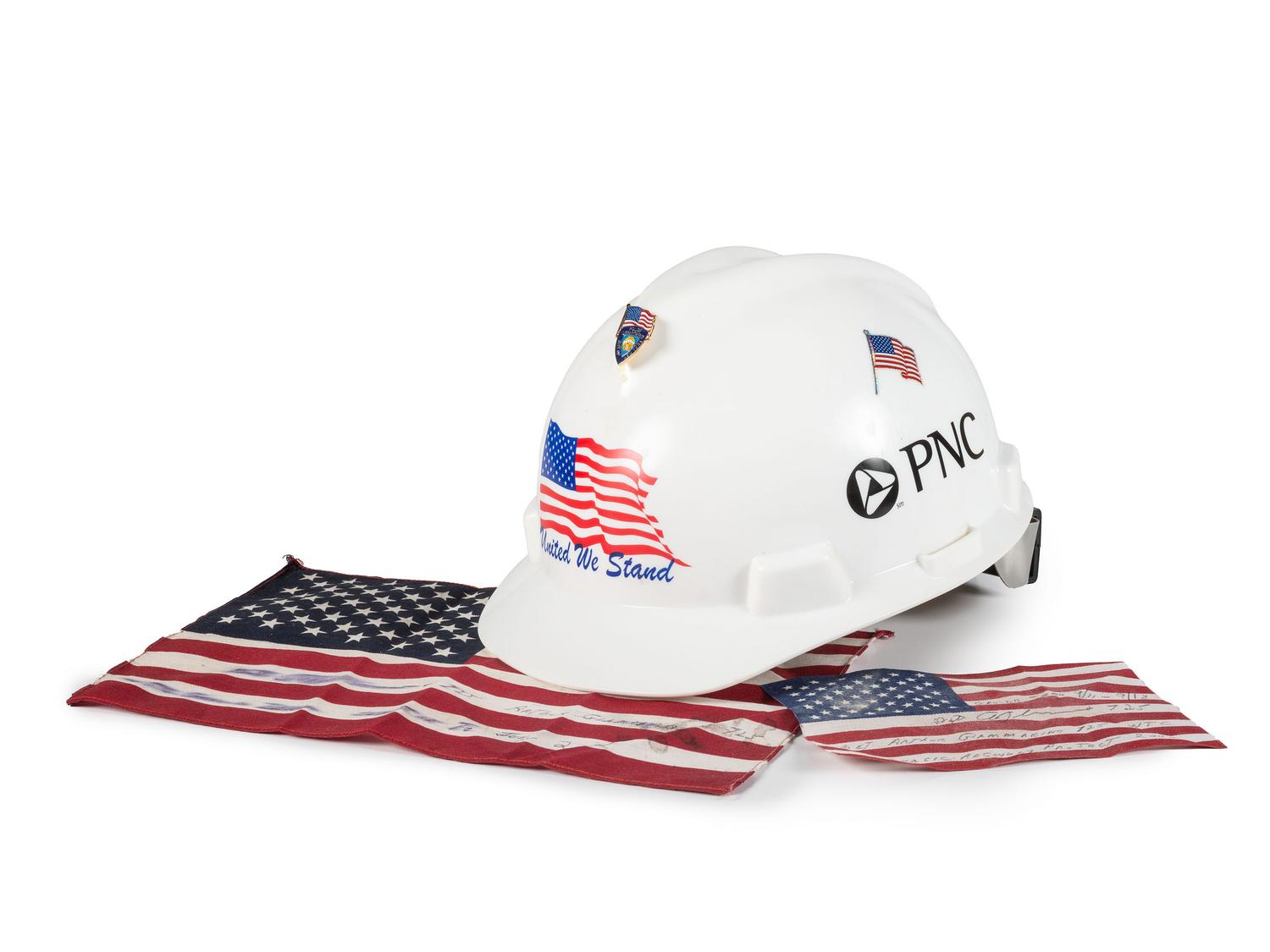 [FLAGS]. A group of items related to the recovery efforts at Ground Zero after September 11, 2011, incl. a helmet worn at the site by retired NYC Detective Arthur Giammarino as he assisted in the recovery efforts.